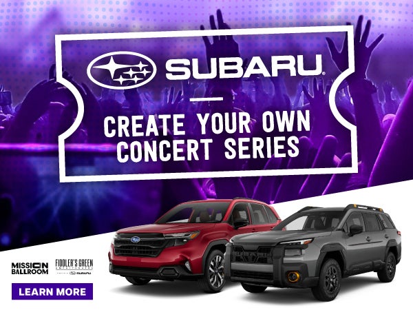 Forester and Outback next to a group attending a concert.